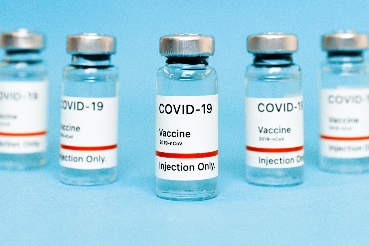 Close-up of COVID-19 vaccine vials labeled for injection on a blue background.